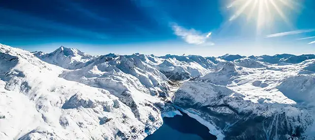 Ośnieżone szczyty i jezioro w dolinie koło Val d'Isère z lotu ptaka