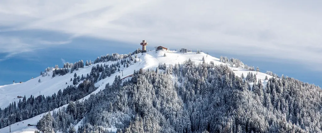 Zaśnieżony szczyt Buchensteinwand z krzyżem Jakobskreuz, stoki i lasy w okolicy Pillersee