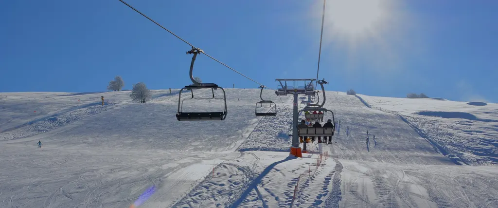 Wyciąg krzesełkowy nad szerokim stokiem Brentonico Ski na Monte Baldo w słoneczny zimowy dzień
