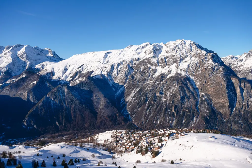 Villard-Reculas na zaśnieżonym zboczu nad doliną, w tle ośnieżone szczyty masywu Oisans