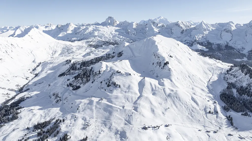 Ośnieżone trasy i wyciągi Le Grand-Bornand z lotu ptaka, w tle łańcuch ośnieżonych szczytów Alp