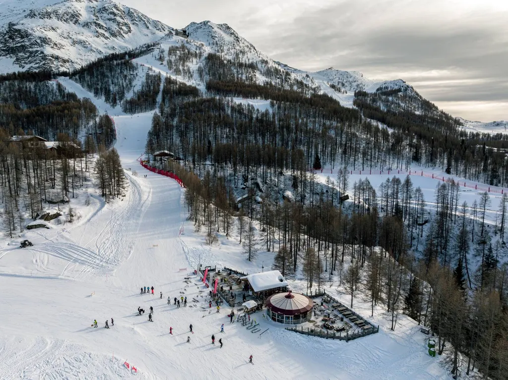 Trasy Skiarea Valchiavenna nad Madesimo z lotu ptaka, wśród modrzewi, w tle ośnieżone szczyty