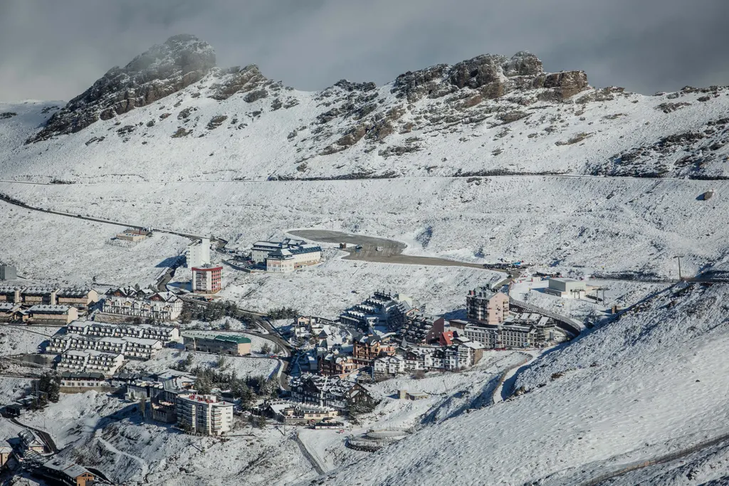 Ośnieżona Pradollano w Sierra Nevada u stóp skalistych grzbietów, w górze stoki ośrodka