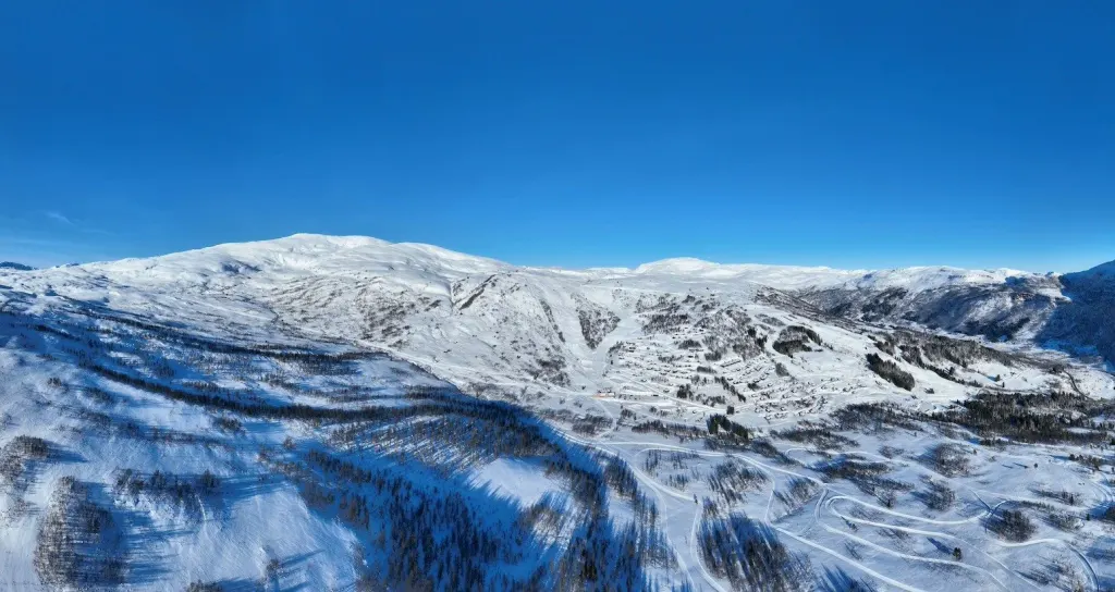 Widok z drona na ośnieżony ośrodek Hodlekve nad Sogndal z trasami i zalesionymi zboczami