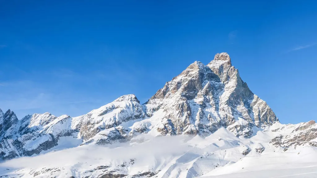 Ośnieżone zbocza nad Breuil-Cervinia zimą, nad nimi szczyt Cervino na tle bezchmurnego nieba