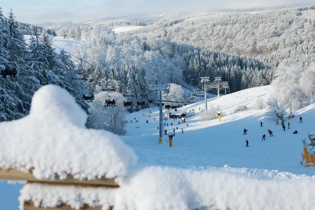 Ośnieżony stok w Altastenbergu z wyciągami i narciarzami, wokół oszronione lasy Sauerlandu
