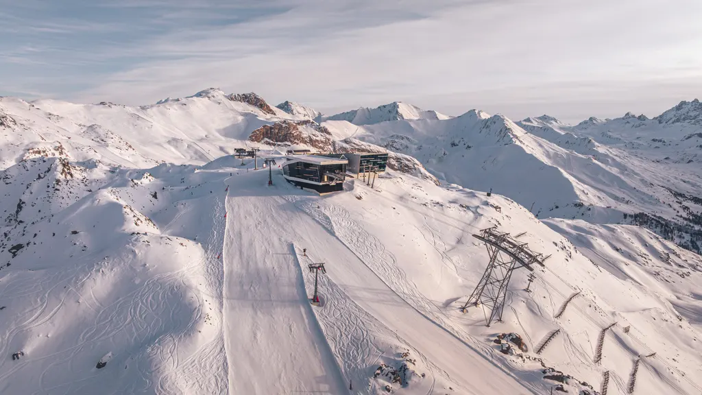 Trasa i górna stacja kolei w Silvretta Arena Ischgl zimą, w tle ośnieżone szczyty Silvretty