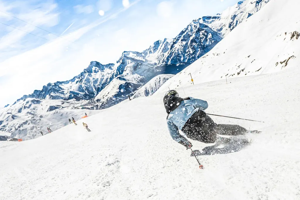 Narciarz na stoku w Alpe d'Huez, w tle zaśnieżone szczyty Oisans
