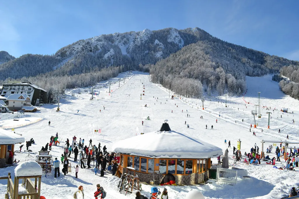 Stok w Kranjskiej Górze z dolną stacją i zaśnieżonymi szczytami Alp Julijskich