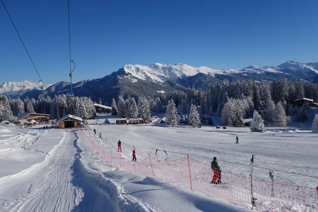 Wyciąg orczykowy i trasy na Brambrüesch nad Chur, za lasem ośnieżone szczyty Alp Gryzońskich