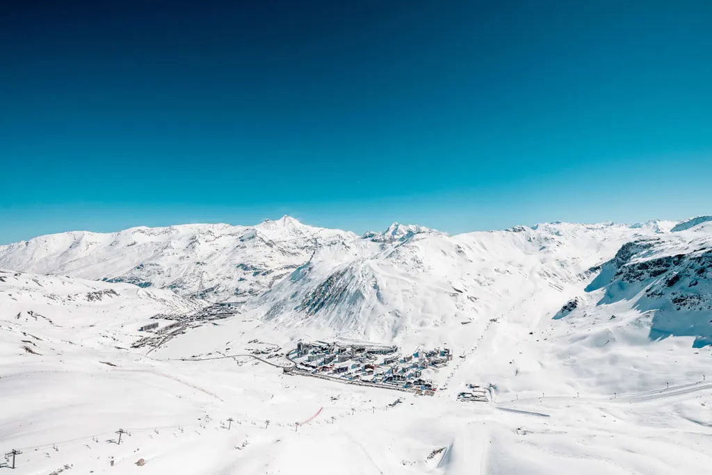 Zimowy widok z góry na Tignes i ośnieżone stoki z wyciągami, w tle szczyty masywu Vanoise