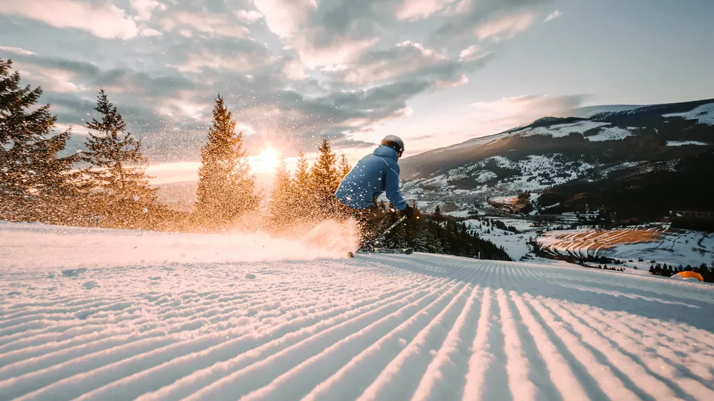 Snowboardzista na przygotowanej trasie w Telgárcie o zachodzie słońca