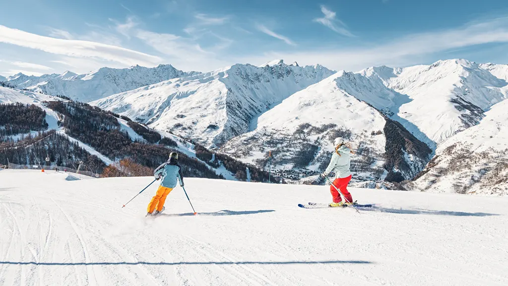 Dwoje narciarzy na wyratrakowanej trasie w Valloire, w tle ośnieżone szczyty masywu Galibier