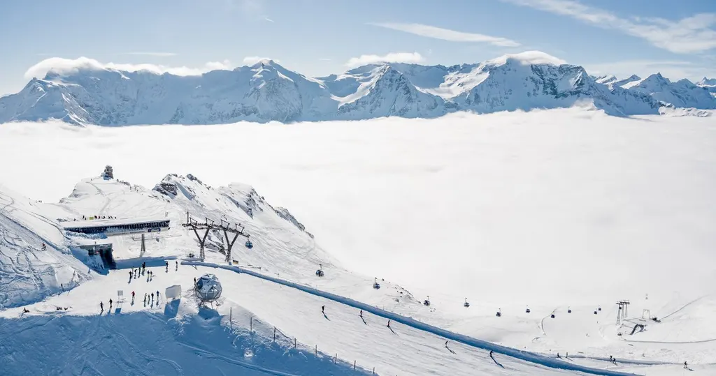 Górna stacja kolei na Kreuzkogel w Sportgastein nad morzem chmur, w tle ośnieżone szczyty Taurów Wysokich