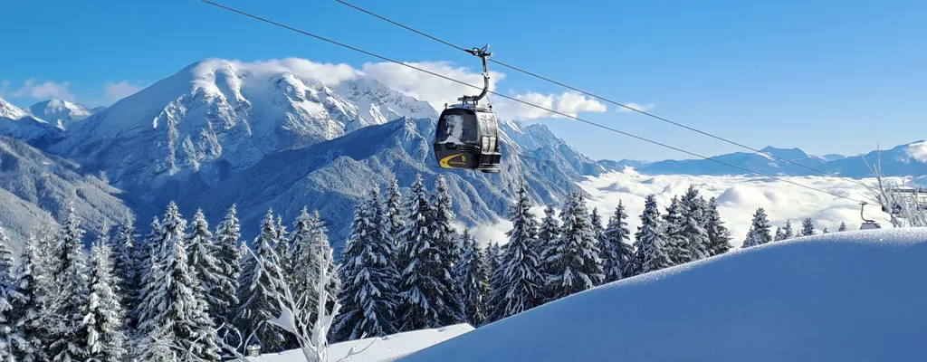 Gondola Rangger Köpfl nad zaśnieżonym lasem w Oberperfuss, w tle ośnieżone szczyty i morze chmur
