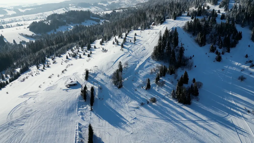 Ośnieżone trasy i wyciągi Ski centrum Oravská Polhora z lotu ptaka wśród świerkowego lasu w słońcu