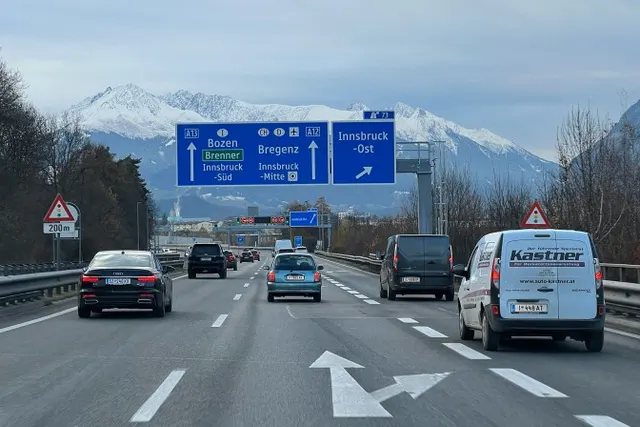 Autostrada w dolinie Innu przed Innsbruckiem, z tablicami w kierunku Brennera i ośnieżonymi szczytami w tle